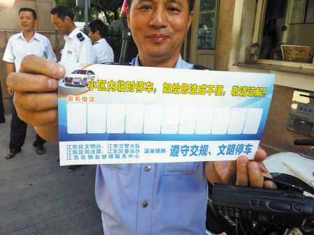 交警展示小区临时停车联系卡。 记者 徐叶 摄