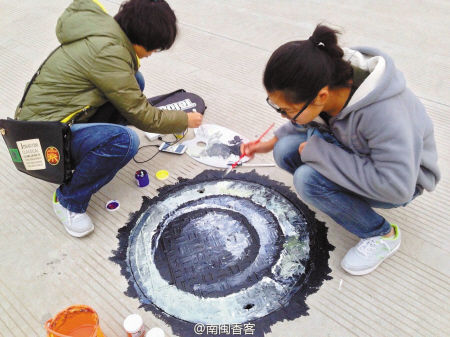 大学生们在窨井盖上作画。