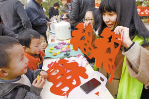 宁波城市学院艺心志愿者向孩子们展示剪好的纸花。记者 徐文杰 摄 