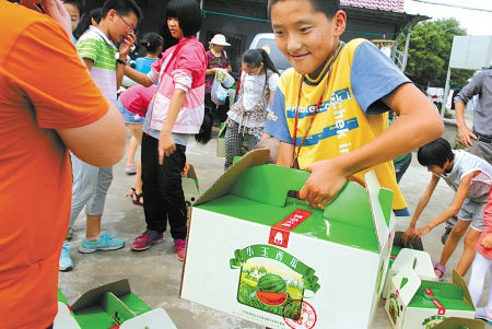 困难家庭的孩子喜领果园赠送的盒装西瓜